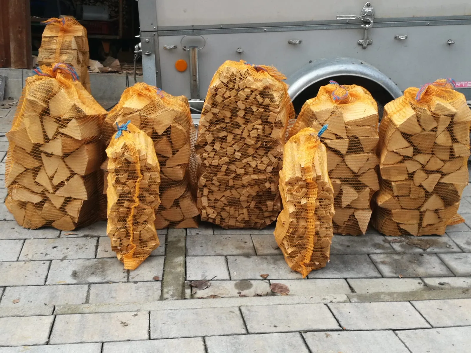 Netzsäcke mit Brennholz vor der Hofeinfahrt